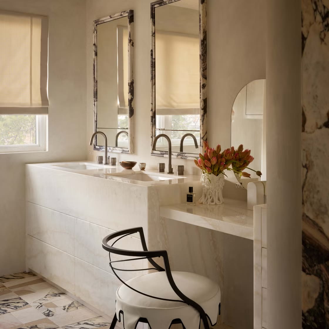 Stone double-sink vanity with tall mirrors and a built-in makeup station